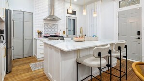 A modern kitchen with white cabinetry, a central island with bar stools, stainless steel appliances, and pendant lighting. - Luxury Rose Manor - Perfect for Bachelorettes! (Columbus)