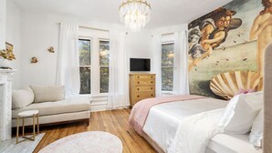 A bedroom with a bed, a sofa, a TV, a dresser, and a painting on the wall. - Luxury Rose Manor - Perfect for Bachelorettes! (Columbus)