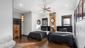 A bedroom with two beds, a brick accent wall, a clock, and a ceiling fan. - Short North Clubhouse w/Hot Tub! Free Parking! (Columbus)