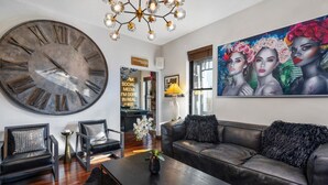 A modern living room with a large wall clock, leather sofas, a coffee table, and a vibrant painting. - Short North Clubhouse w/Hot Tub! Free Parking! (Columbus)
