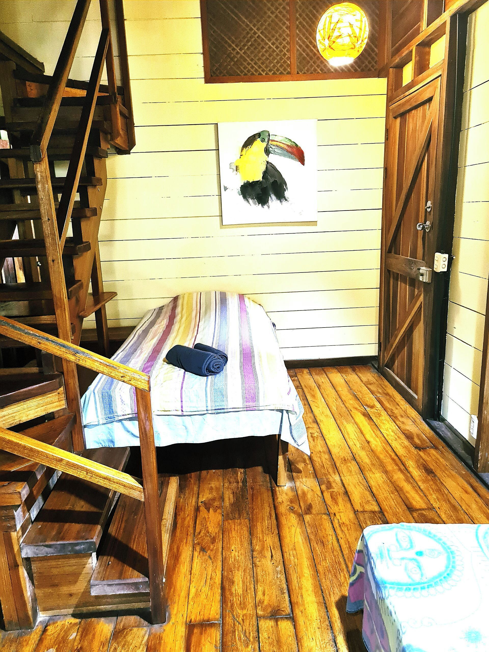 Ein Zimmer mit einem Bett, einer Holztreppe, einer Tür und einem an der Wand befestigten Globus.