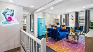 Una sala de estar moderna con un sofá azul, un tapete colorido e instalación artística de neón.