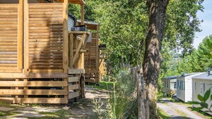 Una fila de casas móviles de madera, con un camino de tierra y vegetación.