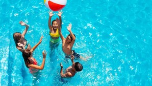 Un grupo de personas jugando con una pelota de playa en una piscina.