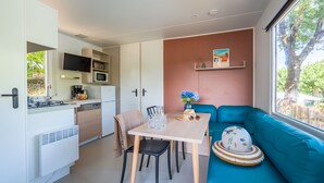 Una cocina compacta con comedor, un sofá color turquesa y un ventanal amplio.
