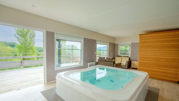 Un spa moderno con jacuzzi, ventanas amplias y vista a follaje.