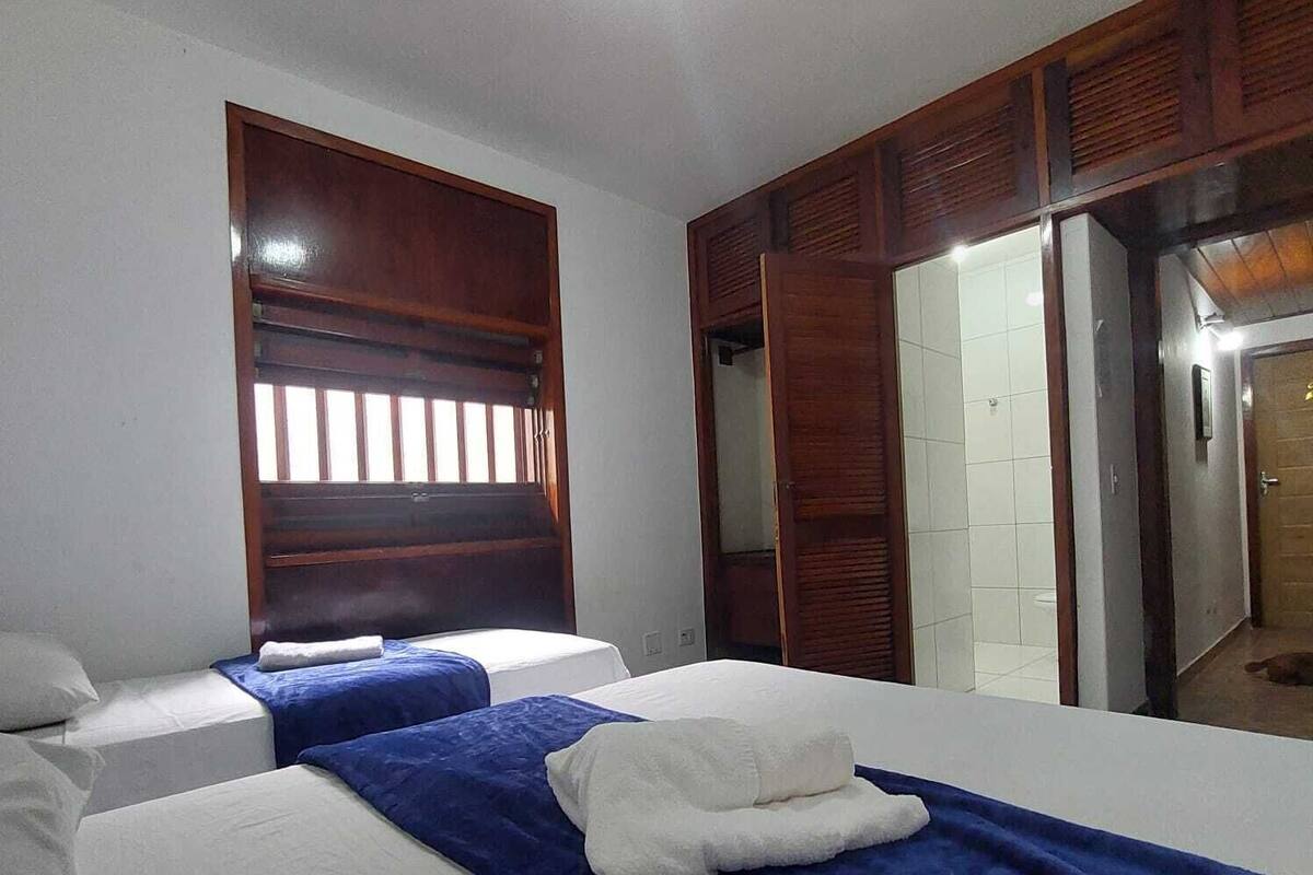 Een hotelkamer met twee bedden, een houten garderobe en een zichtbare badkamer door een open deur.