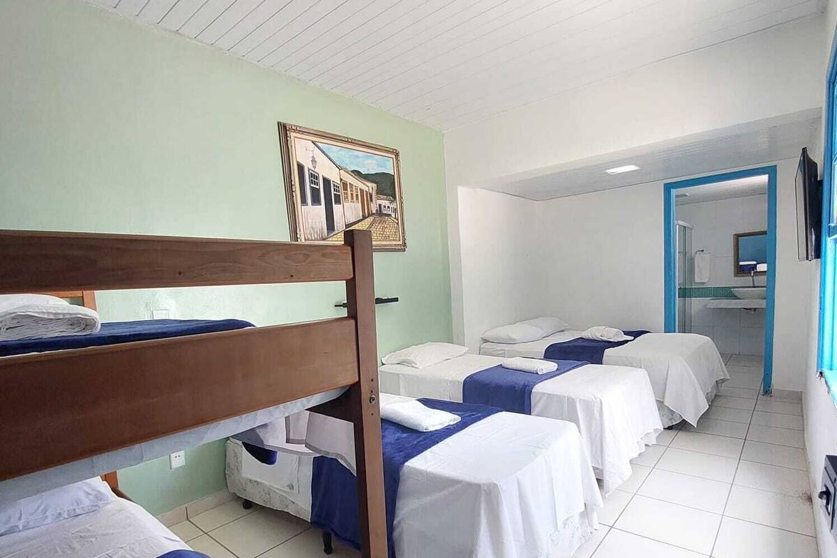 Een slaapzaal met stapelbedden, een badkamer met douche, en een gang naar een andere kamer.