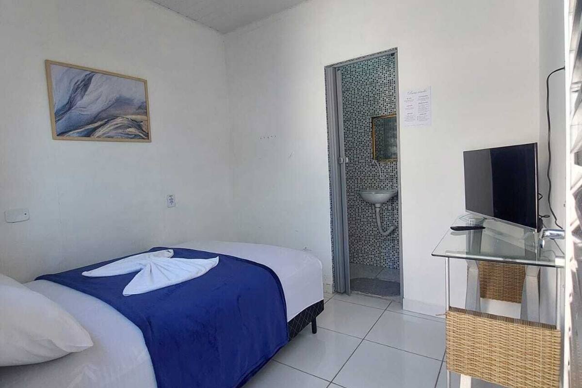 Een hotelkamer met een bed, een televisie op een glazen tafel, een schilderij aan de muur en een deur met een patroon.