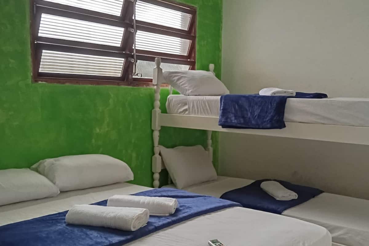 Een slaapkamer met een stapelbed, een raam met zonwering en een airconditioning.