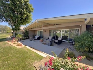 A modern house with a covered patio, outdoor furniture, and a well-maintained garden.