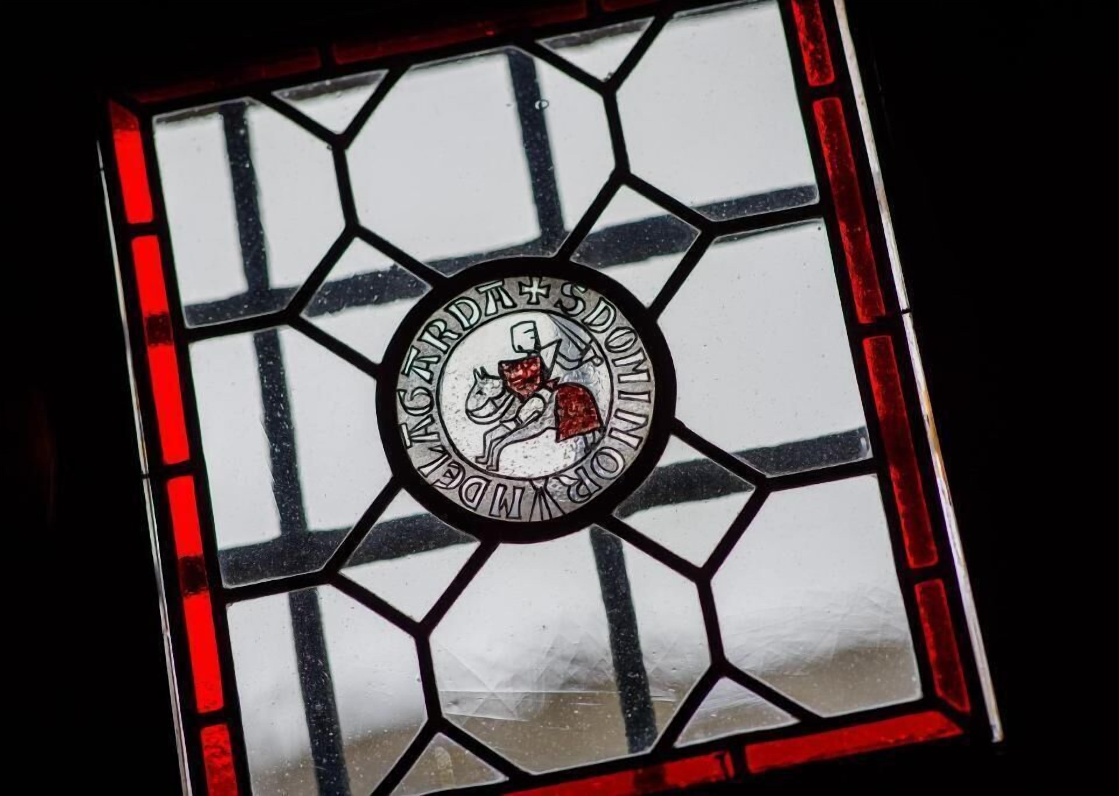 A stained glass window with a circular emblem featuring a horse and rider.