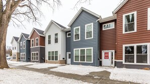 Une rangée de maisons de ville, avec une pancarte « À vendre », une allée en béton et un sol recouvert de neige.
