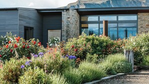 Ein modernes Gebäude mit Steinaußenseite und großen Fenstern, umgeben von einem Garten mit bunten Blumen.