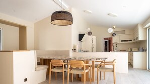 A modern kitchen with a central island, wooden chairs, and pendant lighting.