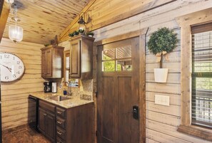 A wooden interior with a kitchen area, including cabinets, a sink, and a clock.