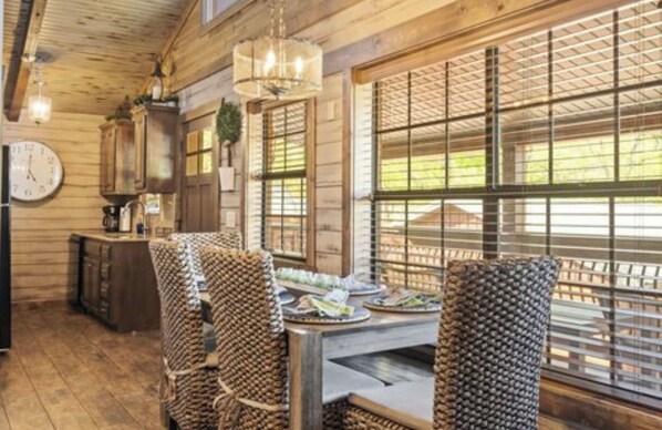 A wooden interior with a dining table, chairs, and a clock on the wall.