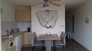 Eine moderne Küche mit Holzausstattung, einem Esstisch mit vier Stühlen und einem Deckenventilator.