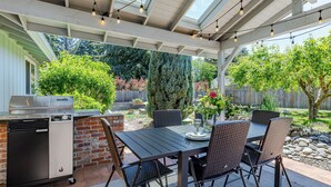 Une terrasse extérieure équipée d’un barbecue, d’une table à manger et de chaises.