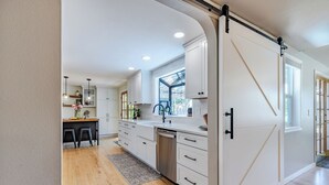 Une cuisine moderne avec des meubles blancs, un lave-vaisselle et une grande fenêtre.