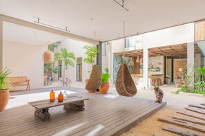 Relax in this open-plan living area with a wooden deck, featuring a rustic table, bench, and wicker chairs.