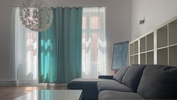 A modern living room with a glass coffee table, grey sofa, teal curtains, and a painting on the wall. - apartment in Katowice center/ 2 min - train station (Katowice)