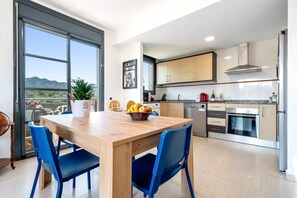 A modern kitchen with a dining area, large windows, and a view of the mountains.