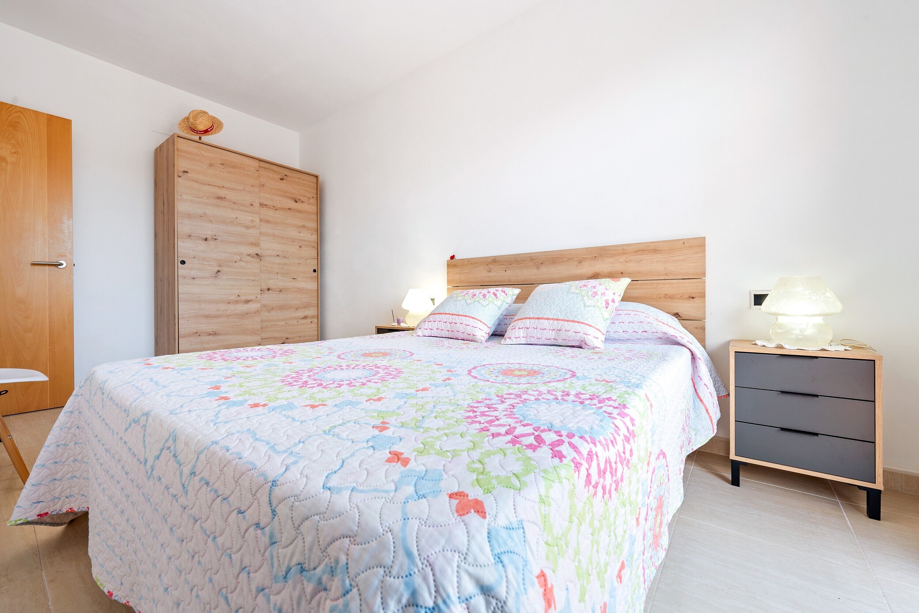 A bedroom with a bed, nightstand, wooden wardrobe, and a door.