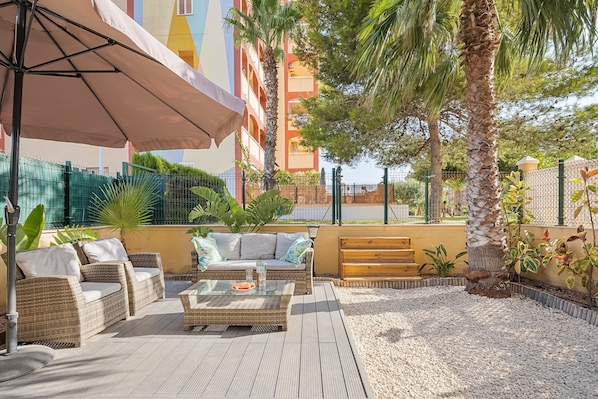An outdoor seating area with wicker furniture, a glass table, and a bench.
