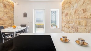 Un comedor con una mesa dispuesta para dos personas, una encimera negra y vistas a través de un ventanal.