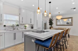 A modern kitchen with white cabinets, a central island, and pendant lighting. - "South Padre Island Family Retreat with Private Pool & Walk to the Beach" (South Padre Island)