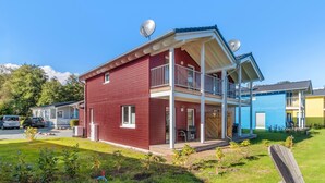 A red two-story house with a balcony, satellite dishes, and a small porch area. - Lovely home in Süssau/Ostsee with sauna (Süssau/Ostsee)