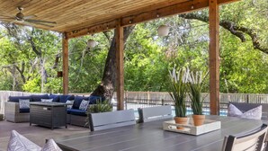 Un patio exterior con una pérgola de madera, zona de estar y una mesa de comedor.