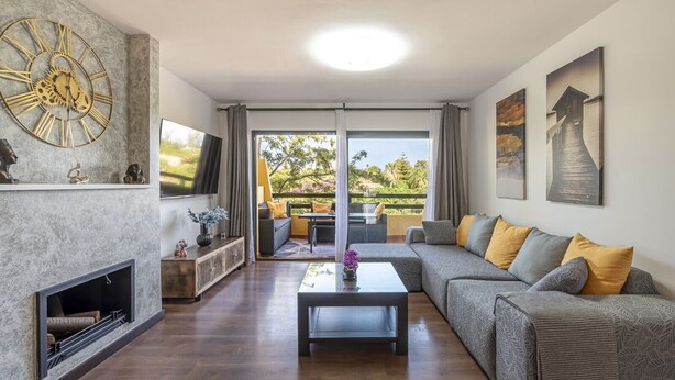 Ein modernes Wohnzimmer mit Kamin, einer großen Wanduhr und einer Couch mit Kissen.