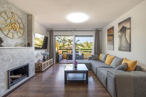 Un salon moderne avec une cheminée, une grande horloge murale et un canapé agrémenté de coussins.