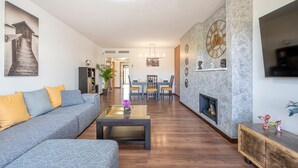 Ein Wohnzimmer mit einer Couch, einem Couchtisch, einem Kamin und einem Essbereich im Hintergrund.