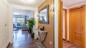 Ein Korridor mit Holzboden, einem wandmontierten Spiegel, einem Konsolentisch mit Dekoration und einer Tür.
