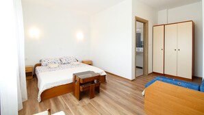 A bedroom with a wooden bed, bedside tables, a wardrobe, and a small wooden bench. - Apartment 2341/115071 (Istria - Fažana), 500m from the beach (Fažana)