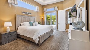 Une chambre avec un grand lit, une table de chevet, une commode et une vue sur l’extérieur.