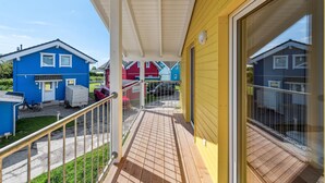 Un balcon donnant sur des maisons aux couleurs vives, un espace abrité et une rambarde en métal.