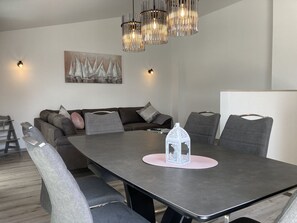 Un espace repas moderne avec une table rectangulaire, des chaises à revêtement gris et une lanterne décorative blanche.