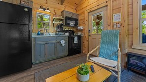 Interior de cabana com cozinha, área de jantar e um espaço de estar aconchegante.