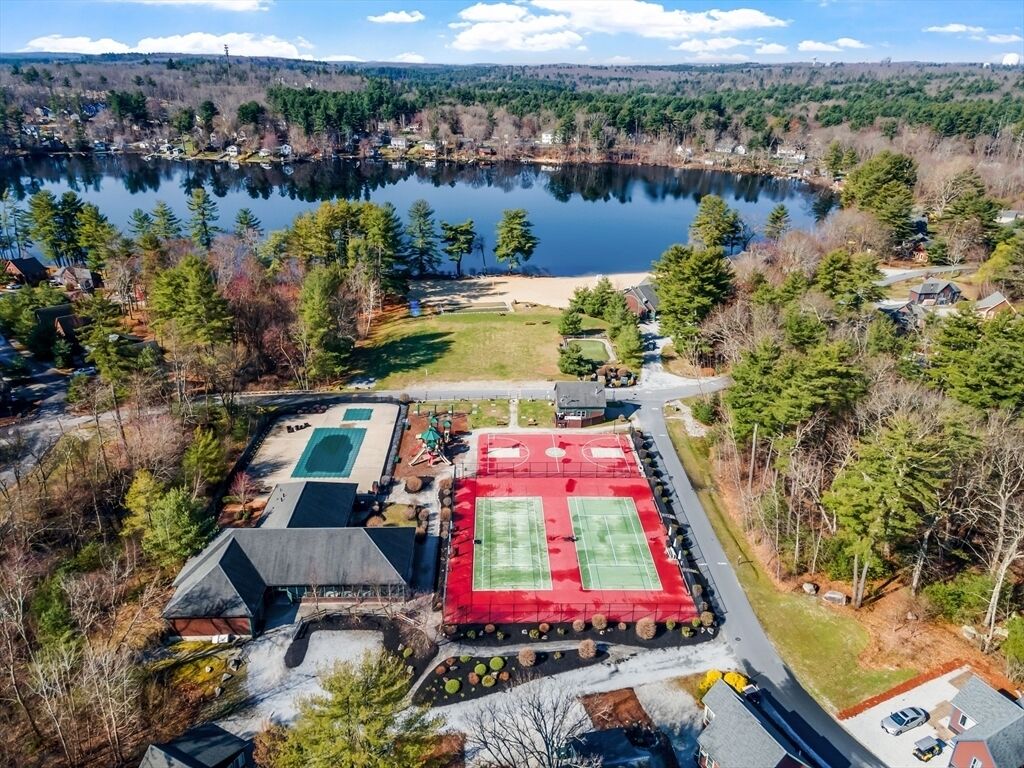 Eine Vogelperspektive auf ein Wohngebiet mit einem See, Tennisplätzen und Häusern.
