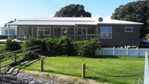 A two-story building with a flat roof, large windows, and a satellite dish. - Absolute beachfront! Sleeps 12+
Built 2011 (Waihi Beach)