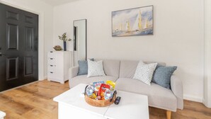 A living room with a sofa, a coffee table with snacks, a painting, and a door. - West Palm Beach Escape (West Palm Beach)