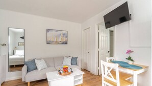 A modern living room with a sofa, coffee table, and a dining area with a chair and table. - West Palm Beach Escape (West Palm Beach)