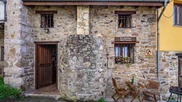 A stone building with a wooden door, a sign reading 'La Ciotina del Forno,' and a small table with chairs outside.
