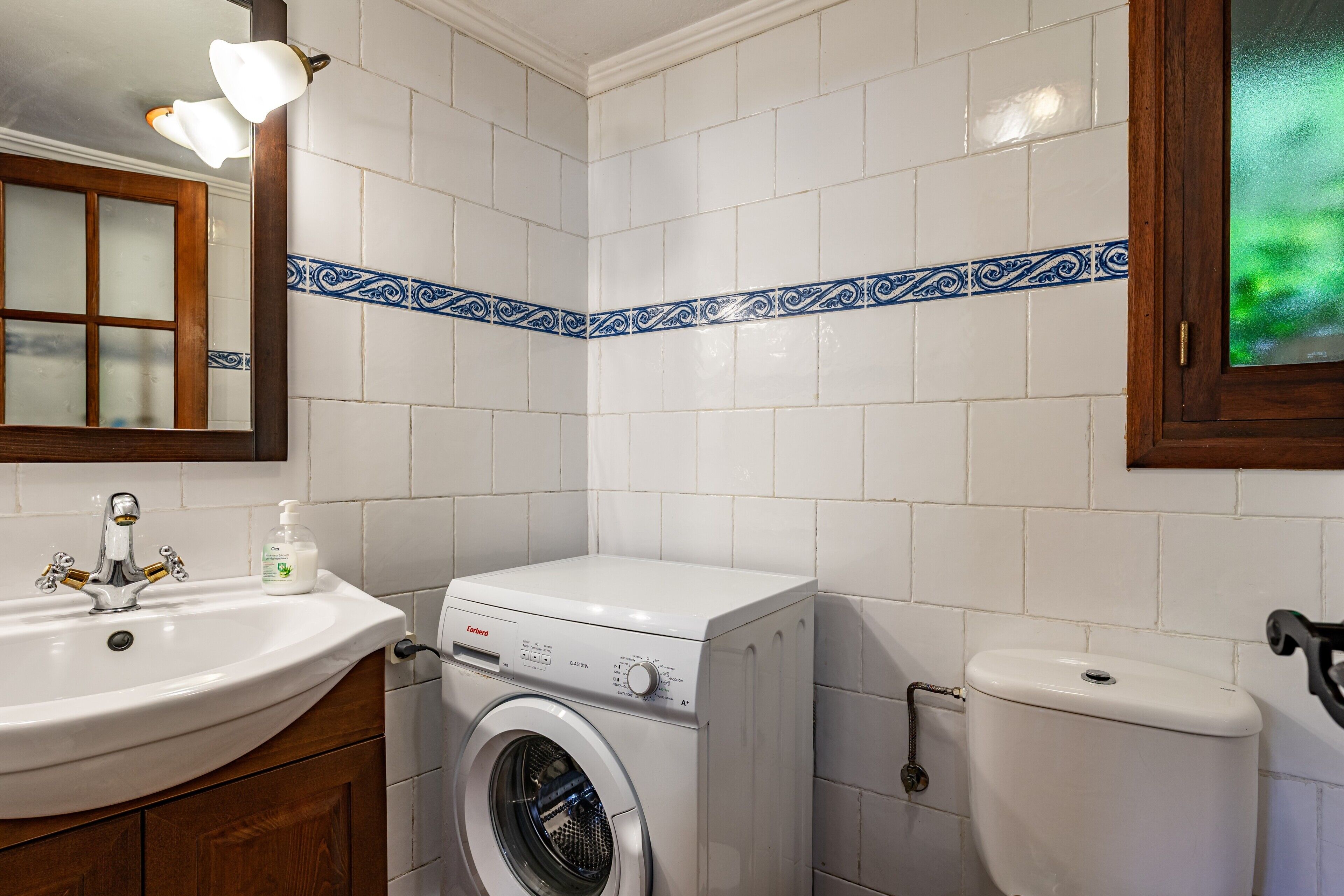 Un baño con lavadora, lavabo e inodoro.
