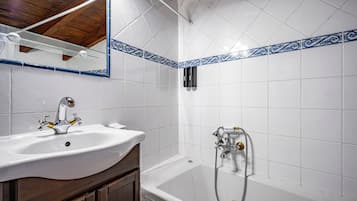 Een badkamer met een wit wastafel, een bad en een douche.