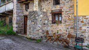 Un edificio de piedra con un letrero que dice 'La Casina del Fornu'. Hay sillas de madera y una pequeña mesa afuera.